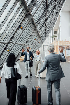 A businessman greets colleagues at the airport terminal