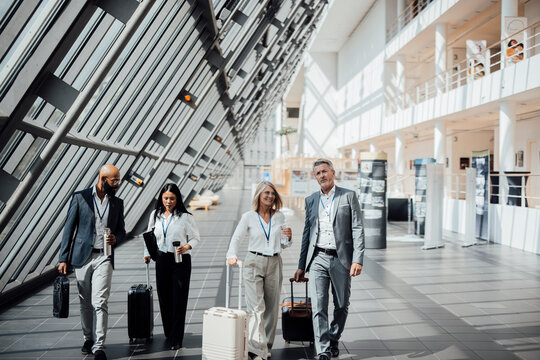 Business team walks through terminal with suitcases