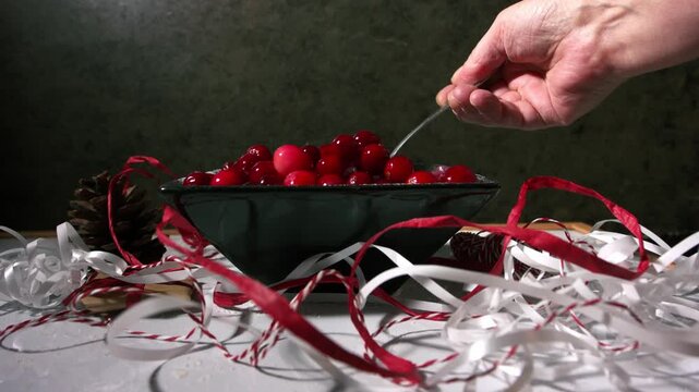 Hand stirring red ripe cranberries in a bowl for Christmas