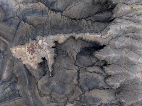Aerial view of the rugged desert badlands with intricate erosion patterns and sedimentary rock layers in the arid landscape of Hanksville, Utah, United States.