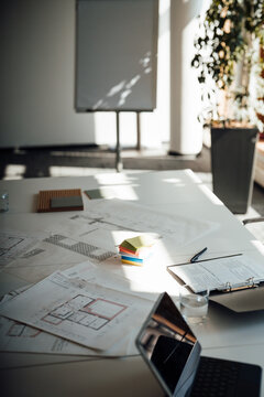 Sunlight illuminates architectural blueprints on an empty office desk