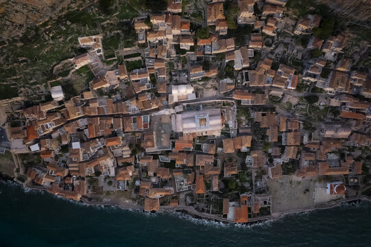 Aerial view of the historic fortified town of Monemvasia with its dense cluster of stone rooftops, narrow streets, and ancient architecture in Monemvasia, Greece.