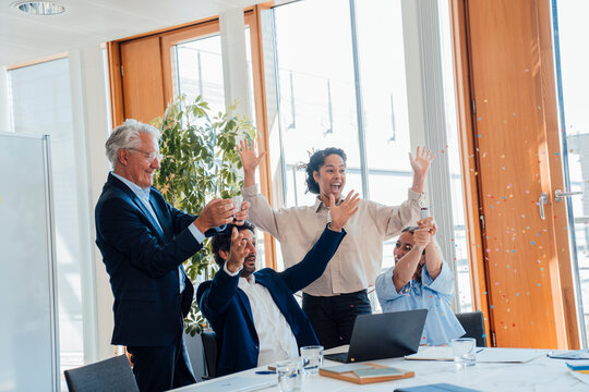 Business colleagues celebrating success with confetti in the office