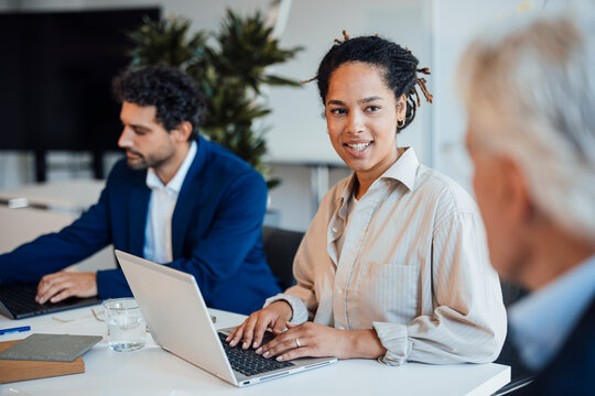 Smiling businesswoman types on a laptop in the office