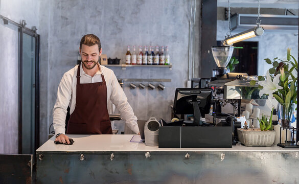 Startup successful sme small business entrepreneur owner man cleaning counter bar coffee shop restaurant. Portrait of young caucasian seller man successful barista cafe owner job modern worker.