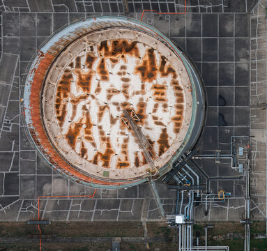 Aerial view of a large industrial storage tank with a weathered, rusty surface and complex piping infrastructure at a chemical plant in Leuna, Saxony-Anhalt, Germany.