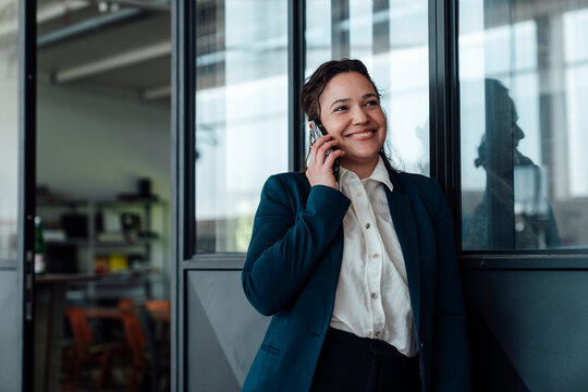Smiling businesswoman talks on smartphone in the carpentry workshop