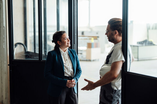 A businesswoman and a carpenter are talking in a workshop