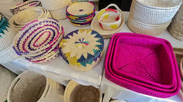 Display of Colorful Handcrafted Straw Baskets and Ethnic Woven Containers at Craft Market, traditional artisan craftsmanship and Pakistani cultural heritage.