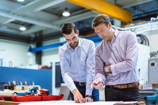 Engineers review blueprint in production hall