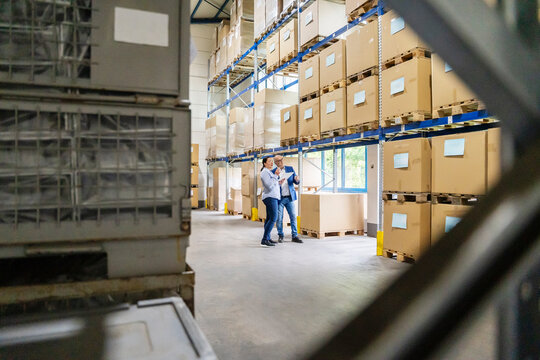 Man and woman with tablet planning logistics in warehouse