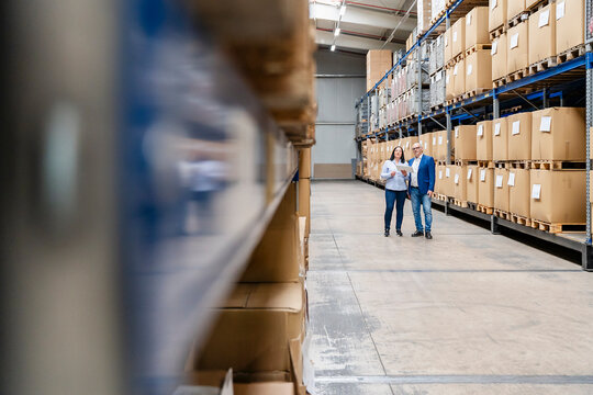 A businesswoman and a businessman check inventory in a warehouse