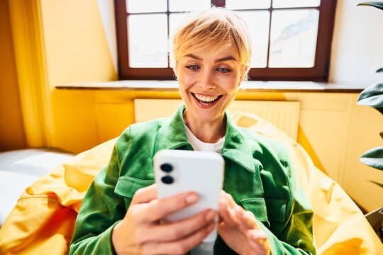 A happy woman reads good news on her smartphone
