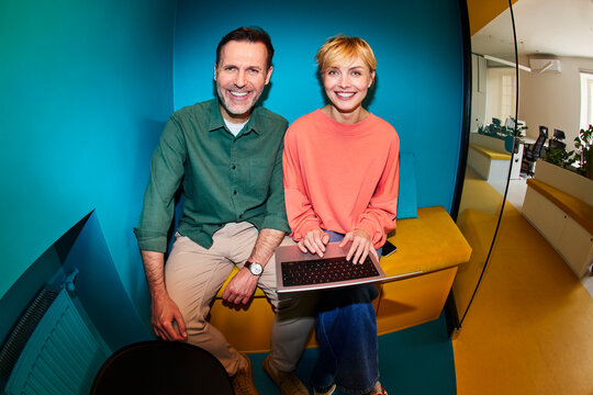 Cheerful colleagues use a laptop in a modern office workspace