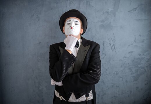 Thoughtful mime artist resting his chin on a gloved hand