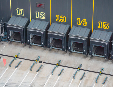 Aerial view of numbered truck loading docks at a modern logistics warehouse with empty loading bays and industrial distribution infrastructure, France.