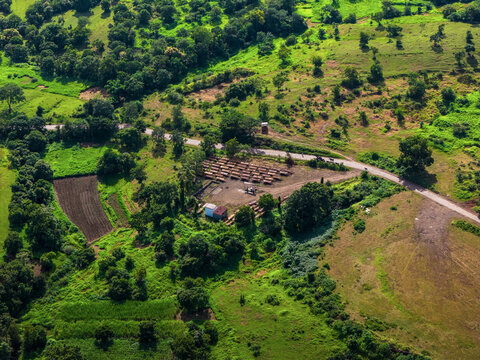 Aerial view of the Athani Sugars Limited Rayat Unit featuring rows of parked trailers and a small industrial building surrounded by lush greenery in Shevalwadi, Maharashtra, India.