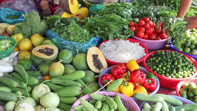 Fresh vegetables at Vietnamese market stall, colorful produce display. Customer choosing fresh ripe greenery. Concept of healthy eating, grocery shopping and local daily life.