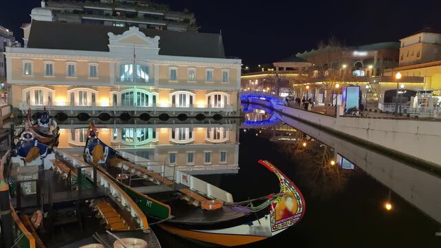 Illuminated canal with traditional boats and historic buildings at night 