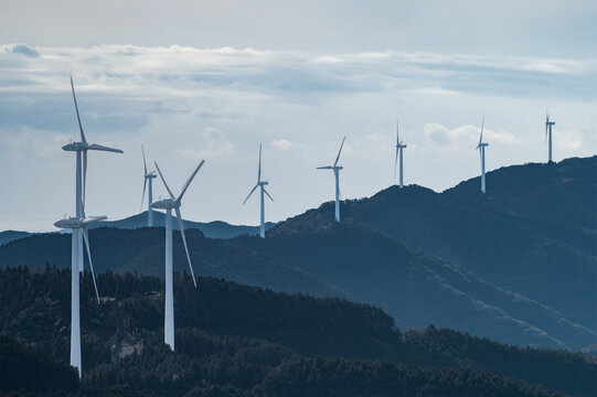 山の稜線に沿って整然と並ぶ風力発電の風車と自然の風景