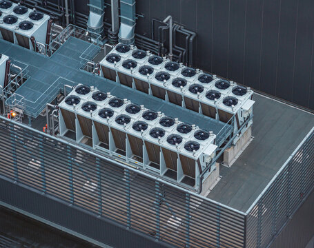 Aerial view of industrial rooftop HVAC cooling units with multiple condenser fans, ventilation ducts and heat management infrastructure in France.
