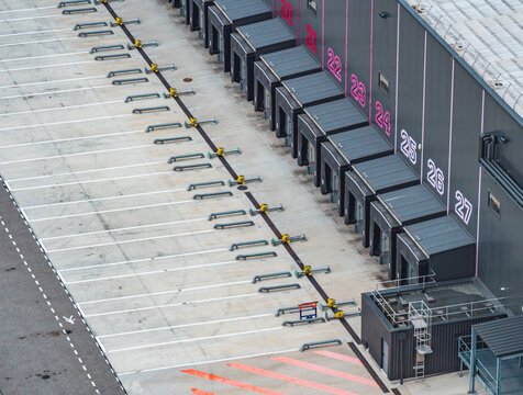 Aerial view of a long row of numbered loading docks and empty truck bays at a modern warehouse distribution and logistics center in France.