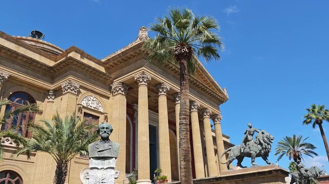 Horizontal video composition framing the marble Verdi bust, grand Corinthian columns, and bronze lion sculpture at Teatro Massimo.