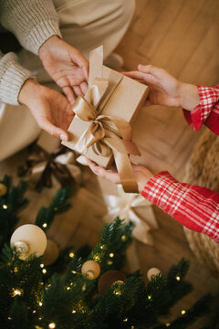 Cute 7-years old girl recieving Christmas present from her mother's hands.