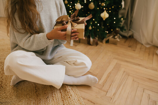 Young beautiful woman relaxing sitting under decorated Christmas tree.