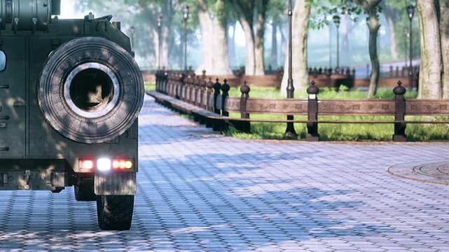 A sturdy military vehicle travels down a quiet, paved path surrounded by lush greenery and trees, showcasing the contrast between a robust machine and peaceful surroundings.