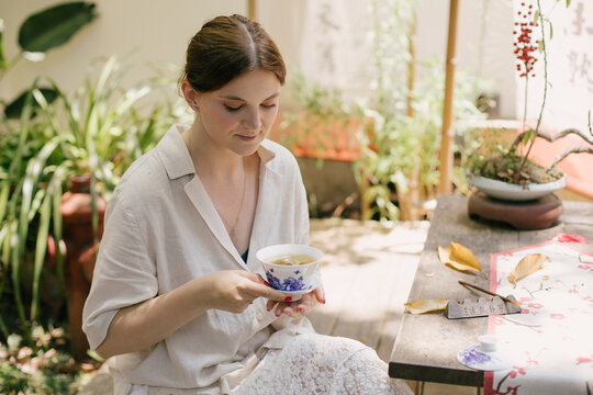 Beautiful young woman drinking jasmin tea sitting in a traditional chinese tea house.