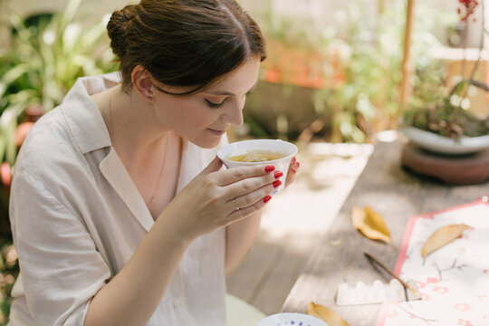 Beautiful young woman drinking jasmin tea sitting in a traditional chinese tea house.