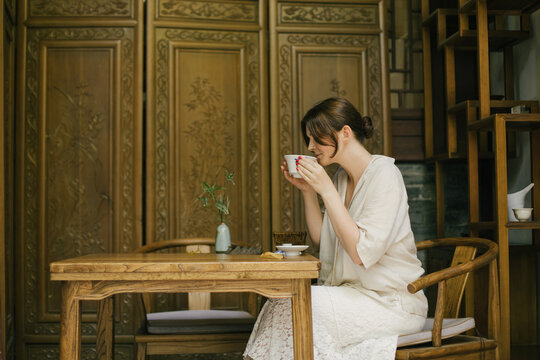 Beautiful young woman drinking jasmin tea sitting in a traditional chinese tea house.