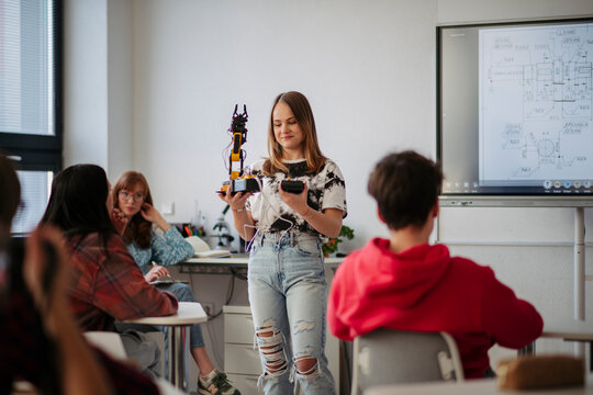 Teen girl explaining robotics project during science and technology class.