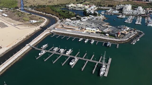 Top view from drone of sailboats and various speed boats in dock. Aerial view of luxure yachts and motorboats moored in a port with clear blue water in summer. Vilamoura, Algarve, Portugal