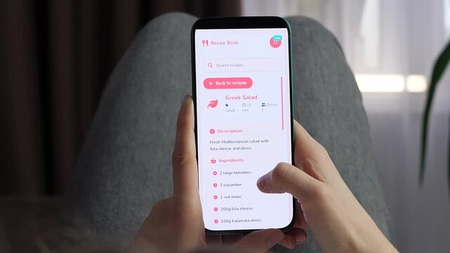 Person browses a mobile recipe app and opens a Greek salad guide, highlighting digital meal planning, healthy cooking and convenient access to step-by-step food preparation.