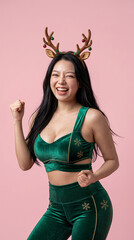 Happy asian woman wearing reindeer antlers headband posing on pink background © iz_zi
