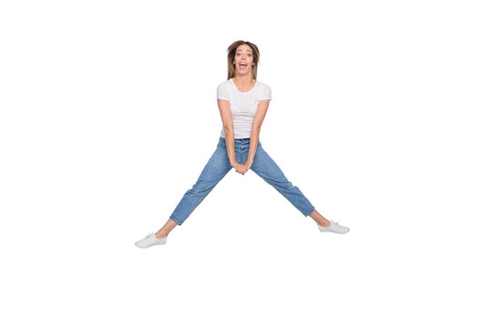 Full length body size photo of crazy funny cute nice attractive girl jumping trying to do splits while isolated with white background