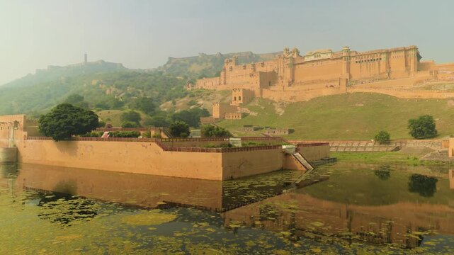Panoramic view of majestic amber fort complex located on hilltop in jaipur india reflecting in maota lake at sunrise.