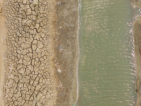 Aerial view of a shrinking river with dry, cracked mud banks during the dry season in Kedung, Central Java, Indonesia.