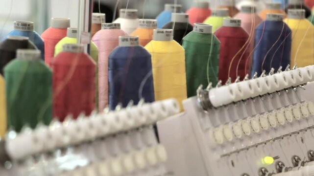 Rows of Colorful Thread Spools on Industrial Embroidery Equipment. The footage documents textile equipment, material handling, stitching or machine controls in a workshop.