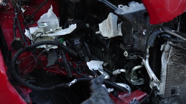 Close up of severely damaged front end of a car after a collision with crushed engine compartment broken components and extensive impact damage from a serious road accident