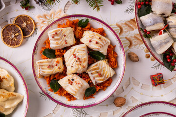 Classic Christmas food medley on a decorated table. Fish, dumplings stuffed with cabbage and mushrooms, cheesecake, and ham. © gkrphoto