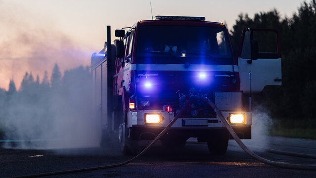Car Crash Traffic Accident. a Front View of a Fire Engine standing on Smoke-filled Road, With Blue Emergencys Flashing and Hoses Connected as Emergency Services Secure the Site After a Collision.