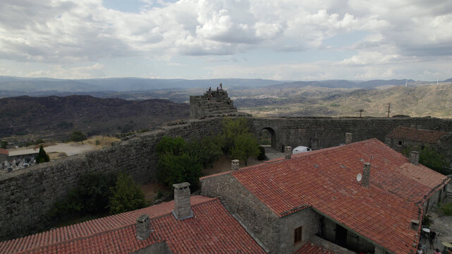 Aerial view of the historic fortified village of Sortelha with its stone walls and terracotta rooftops set against a mountainous landscape in Sortelha, Distrito da Guarda, Portugal.