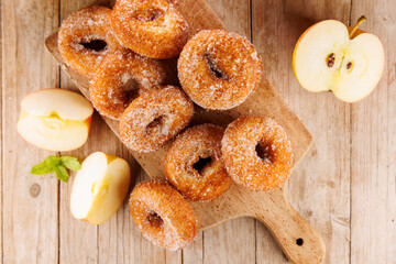 Naklejka na ściany i meble fresh homemade apple cider donuts sprinkled with sugar on wooden board with fresh apple slices