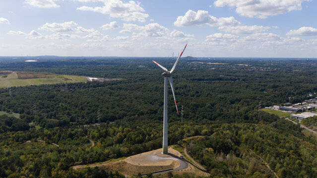 Aerial view of the wind turbine on Halde Hoppenbruch surrounded by dense forest and rolling hills, Herten, North Rhine-Westphalia, Germany.