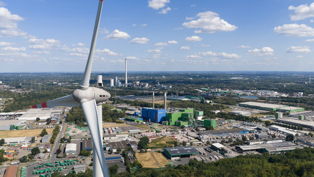 Aerial view of a wind turbine on Halde Hoppenbruch overlooking the industrial landscape and power plant facilities in Herten, North Rhine-Westphalia, Germany.