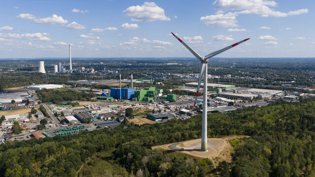 Aerial view of Halde Hoppenbruch with its prominent wind turbine overlooking the industrial landscape and urban area of Herten, North Rhine-Westphalia, Germany.
