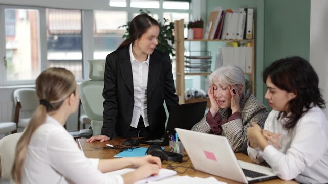 Young woman stands at office desk and scolds group of upset women in office 